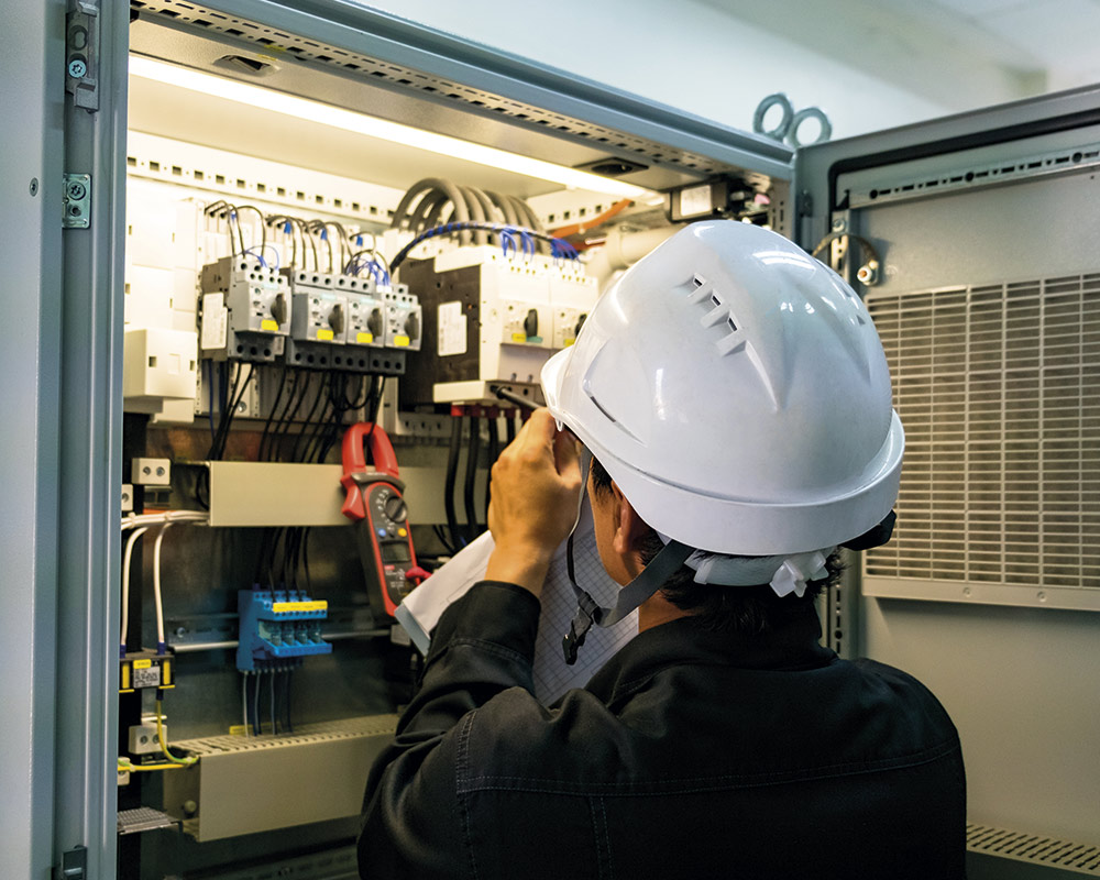 electrician with white helmet installing new circuit panels at new construction house houston tx